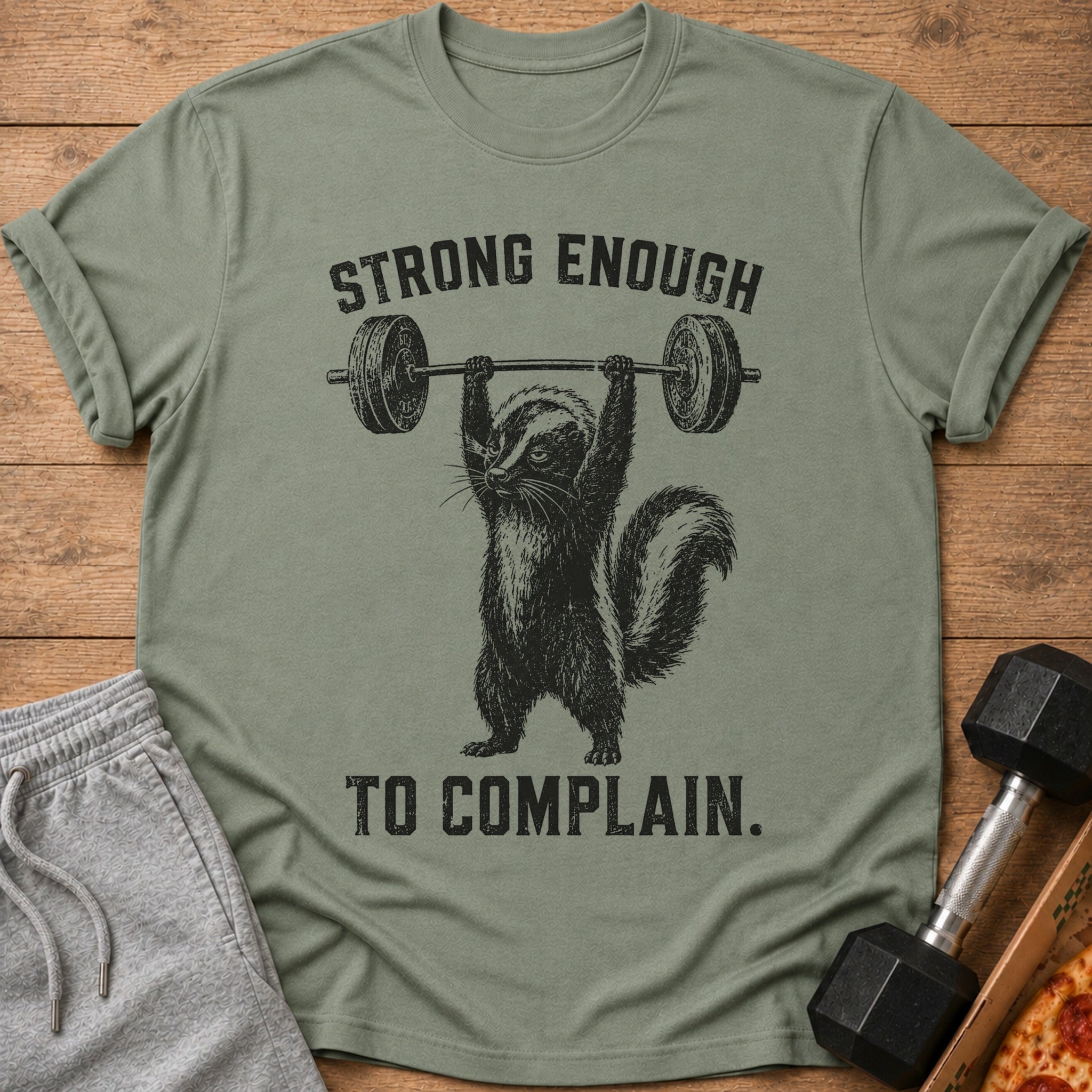 Green t-shirt with a skunk lifting a barbell and text that reads "STRONG ENOUGH TO COMPLAIN."
