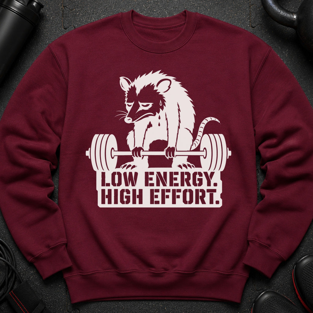 Maroon sweatshirt with white graphics of a tired opossum lifting a barbell and text.
