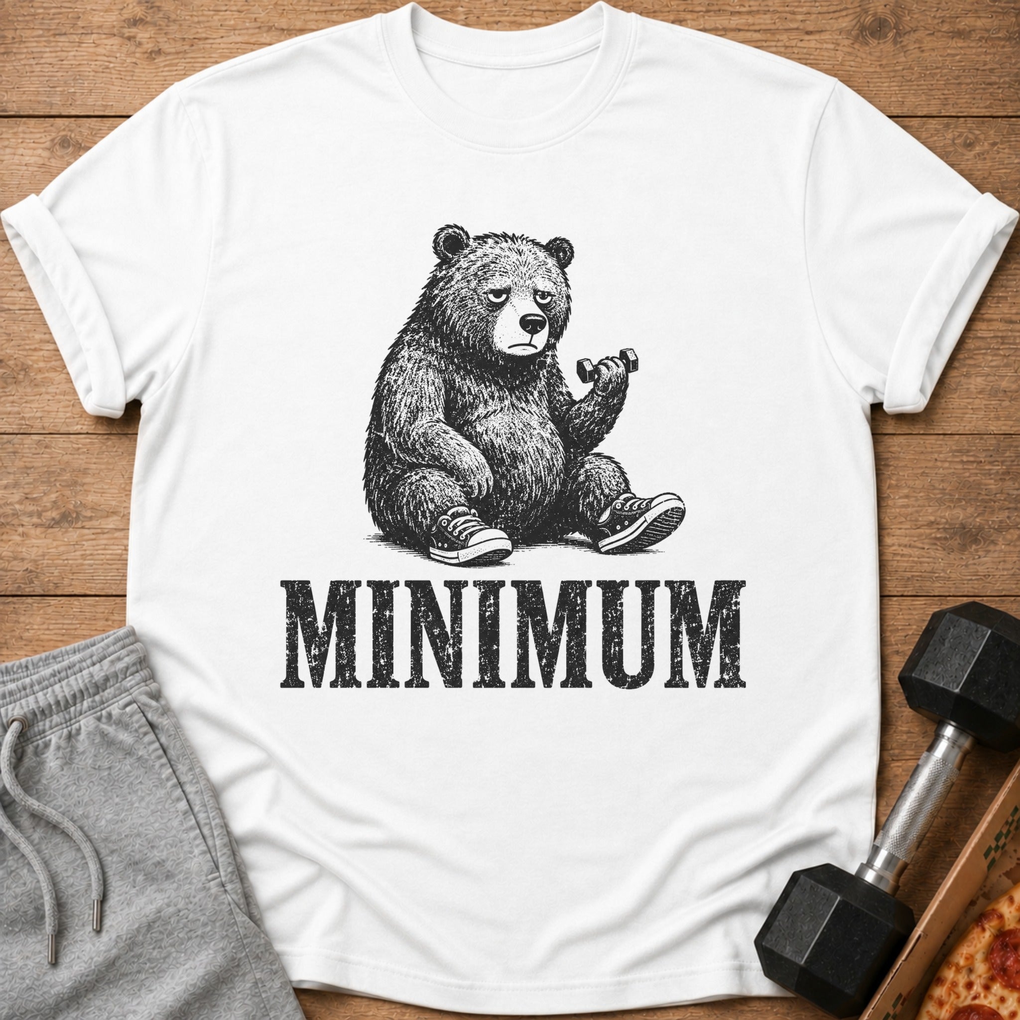 White t-shirt with drawing of a tired bear lifting a dumbbell and the word MINIMUM.