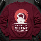 Maroon sweatshirt with a distressed graphic of a kettlebell, smiling, and text "Lifting in Silent Disapproval".