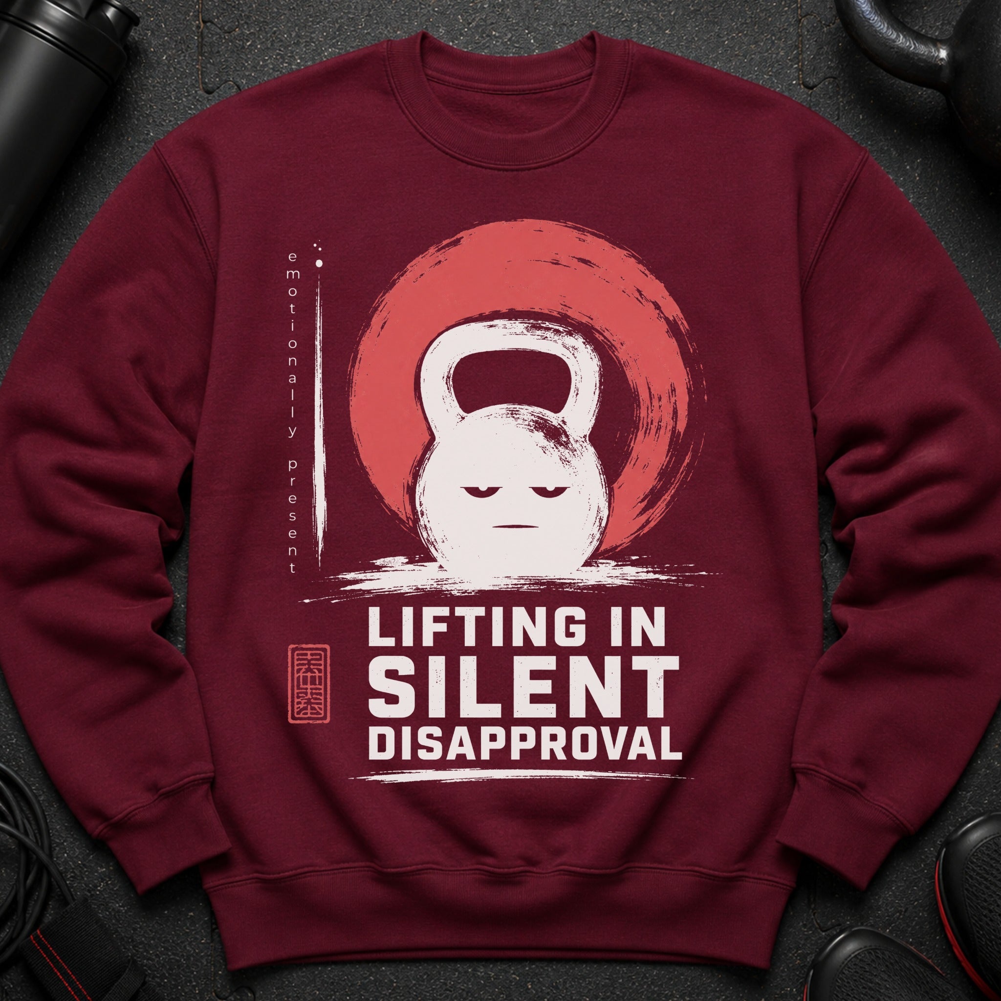 Maroon sweatshirt with a distressed graphic of a kettlebell, smiling, and text "Lifting in Silent Disapproval".