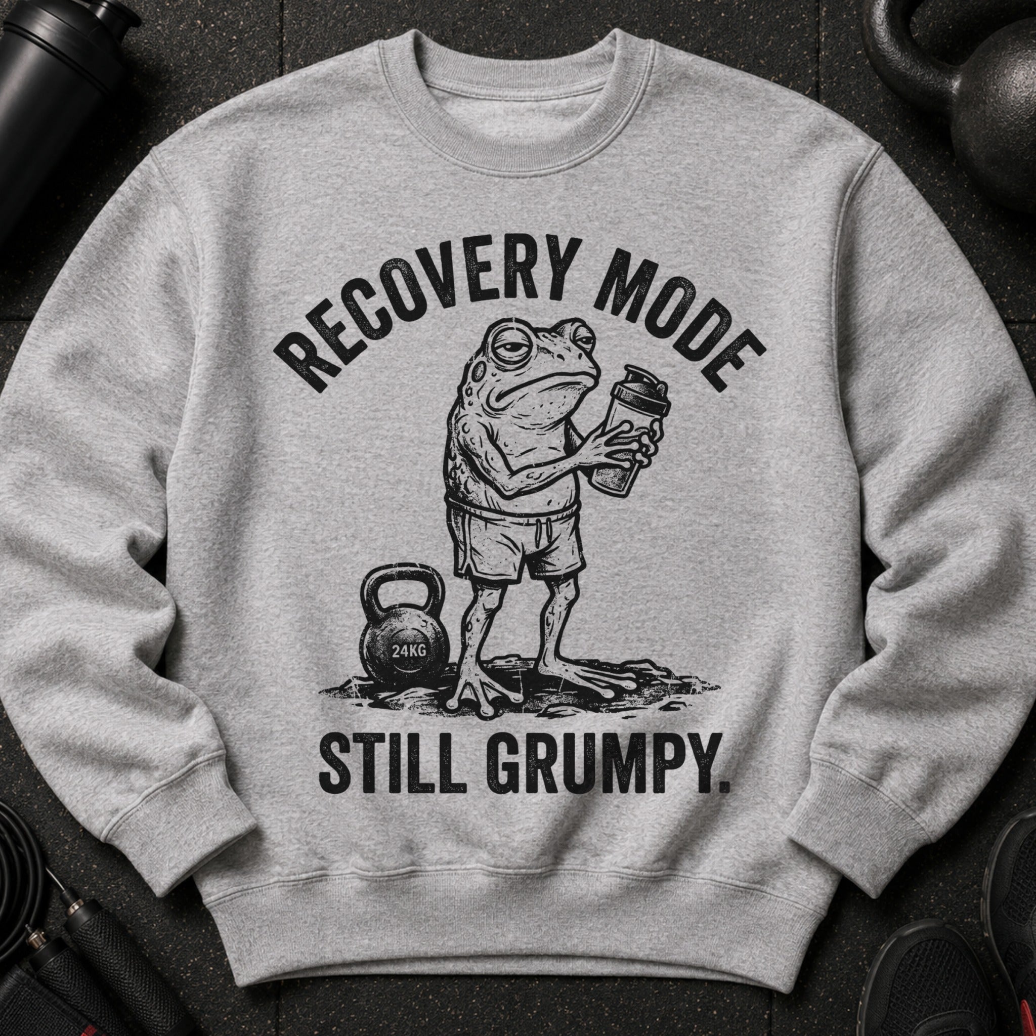 Grey sweatshirt with a drawing of a grumpy frog holding a shaker bottle and the text "RECOVERY MODE STILL GRUMPY."