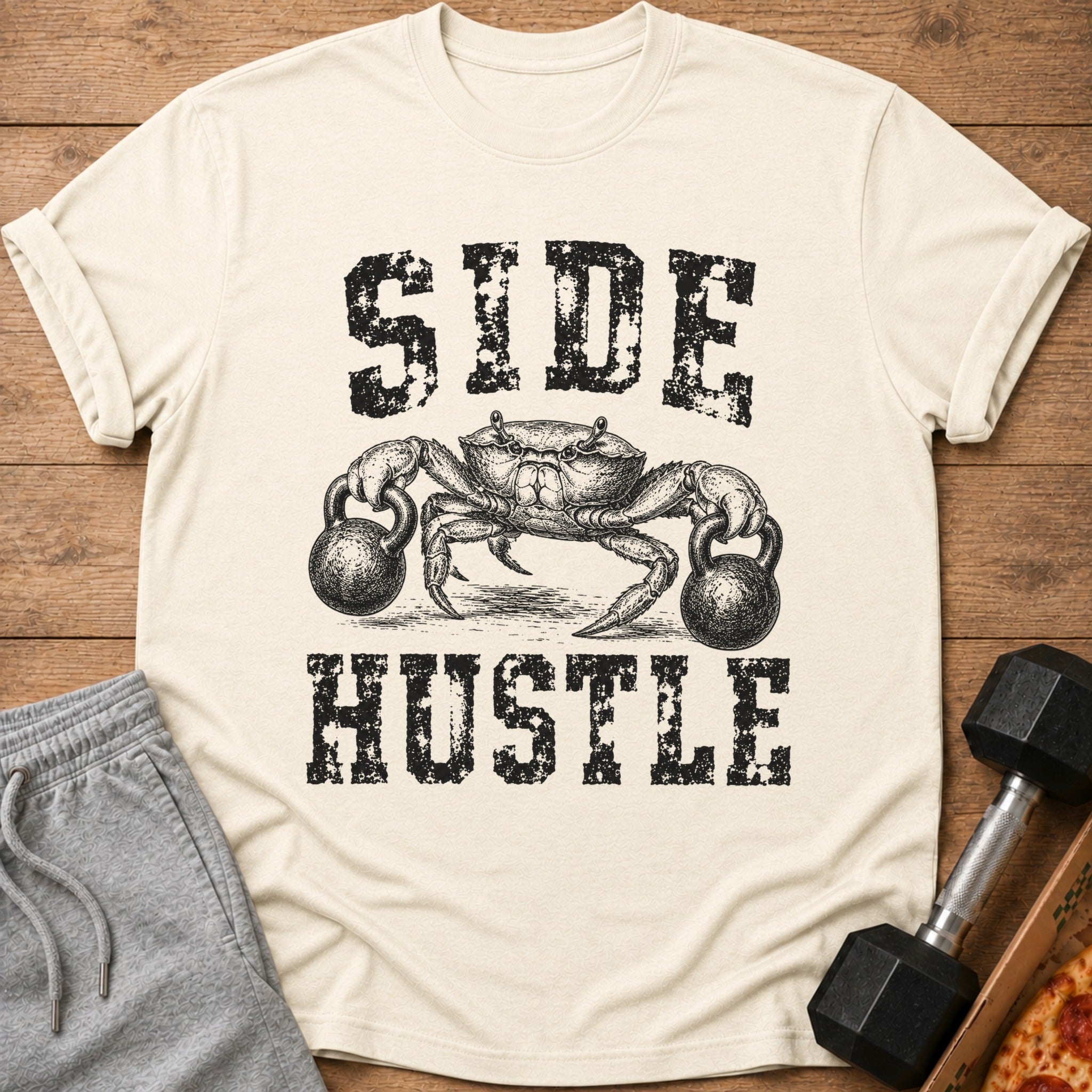 Crab lifting kettlebells with "SIDE HUSTLE" text on a cream t-shirt.