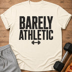 Cream t-shirt with black text "BARELY ATHLETIC" and dumbbell graphic.