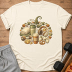 Cream t-shirt with a pumpkin graphic made of dumbbells, headphones, coffee, and snacks.