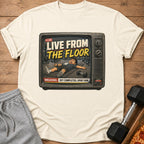 T-shirt graphic of a vintage TV with a person lying exhausted on a mat, "Live from the Floor."