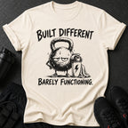 T-shirt with distressed kettlebell graphic and text "BUILT DIFFERENT BARELY FUNCTIONING."