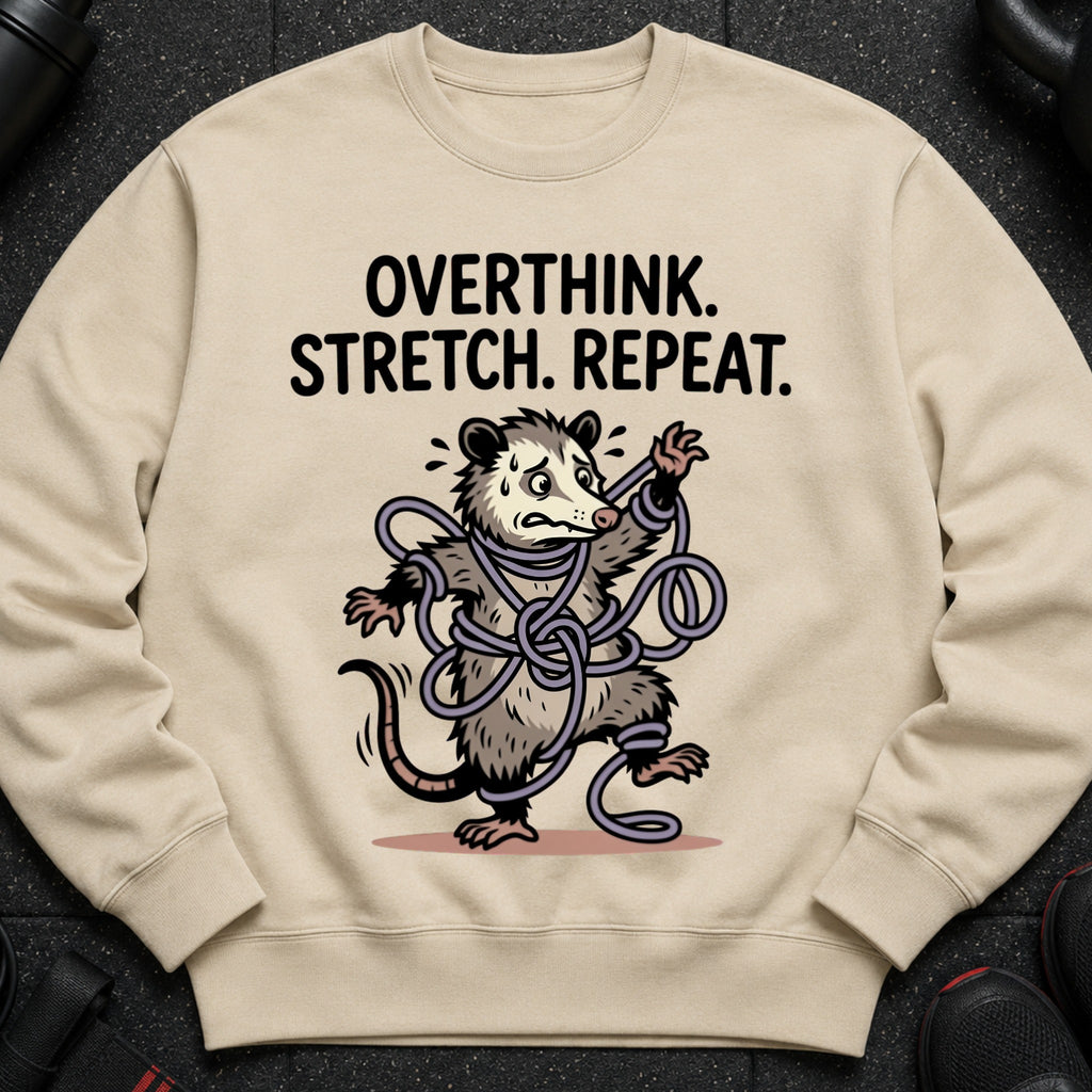 Light tan crewneck sweatshirt with a cartoon possum tangled in purple rope and the text "OVERTHINK. STRETCH. REPEAT."