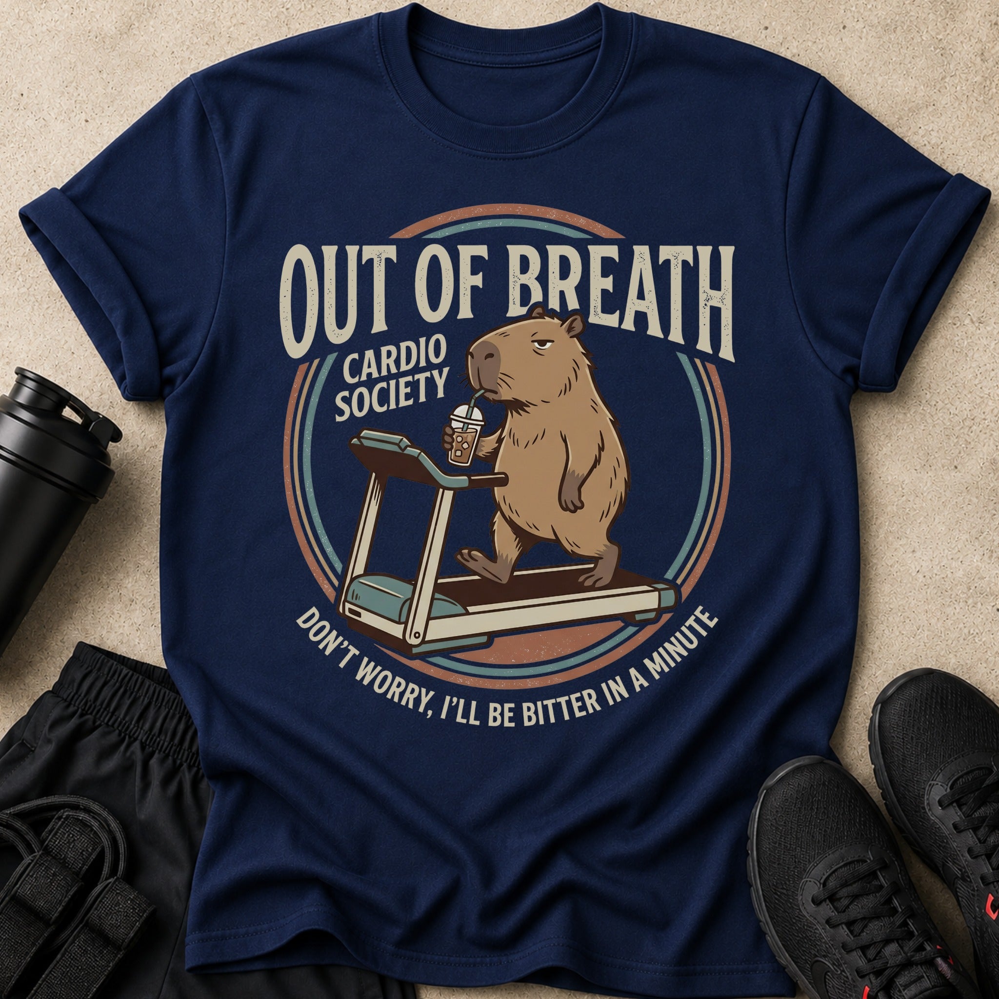 Navy t-shirt with a capybara on a treadmill drinking iced coffee, text reads "Out of Breath Cardio Society".