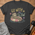 Sloth wearing heart sunglasses floats on a pink and yellow inner tube with "Go With The Slow" text.