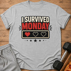 Grey t-shirt with "I survived Monday" text and pixelated hearts.