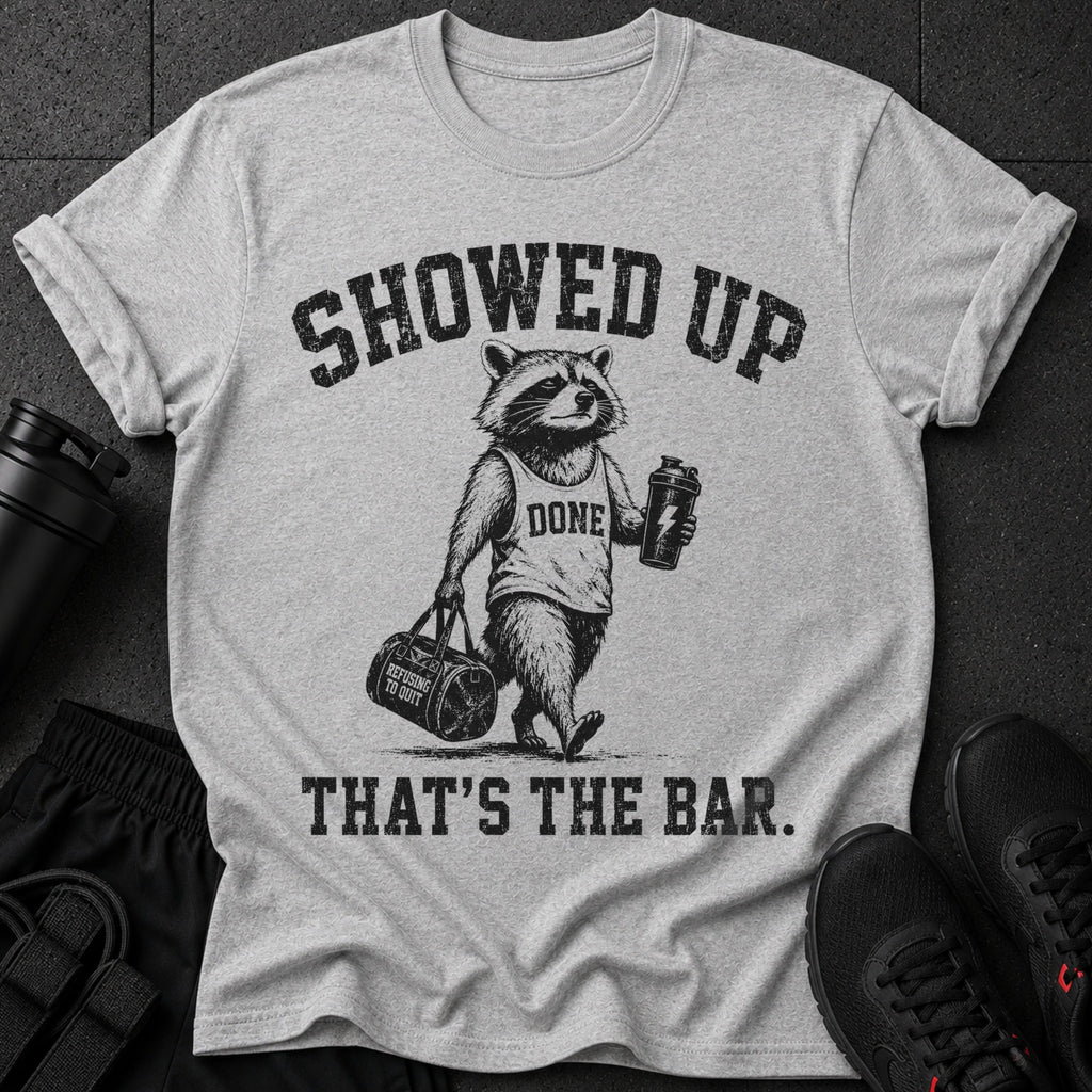 Grey t-shirt with a raccoon graphic, saying "SHOWED UP DONE THAT'S THE BAR."