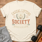 Cream t-shirt with "CASUAL LIFTERS SOCIETY" text, a sloth, and gym graphics.