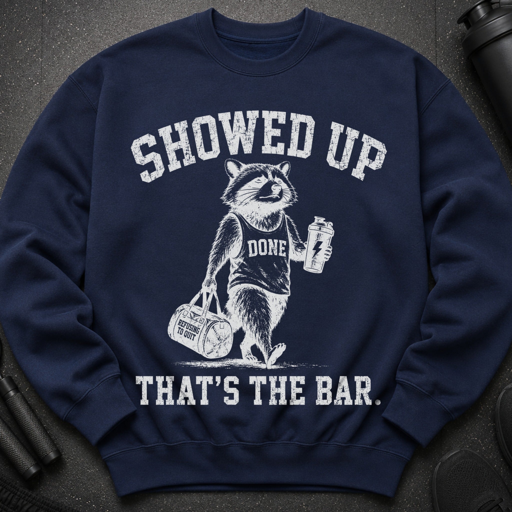 Navy sweatshirt with raccoon graphic and text: SHOWED UP, DONE, REFUSING TO QUIT, THAT'S THE BAR.