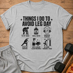 Grey t-shirt with "Things I Do To Avoid Leg Day" and six humorous workout icons.
