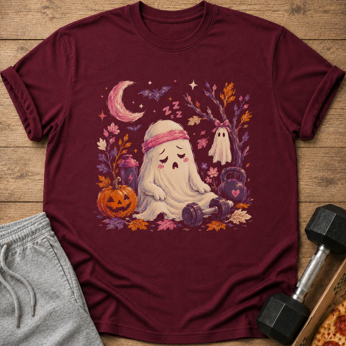 Maroon t-shirt with a tired ghost workout design, moon, pumpkin, and autumn leaves.