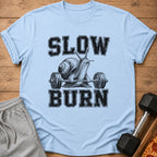 Light blue t-shirt with a snail lifting weights and text that reads "SLOW BURN".