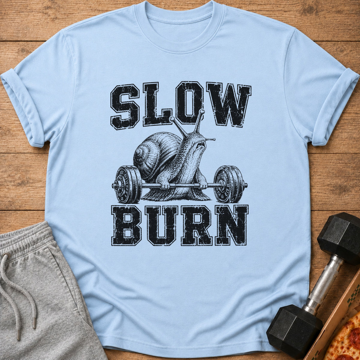 Light blue t-shirt with a snail lifting weights and text that reads "SLOW BURN".