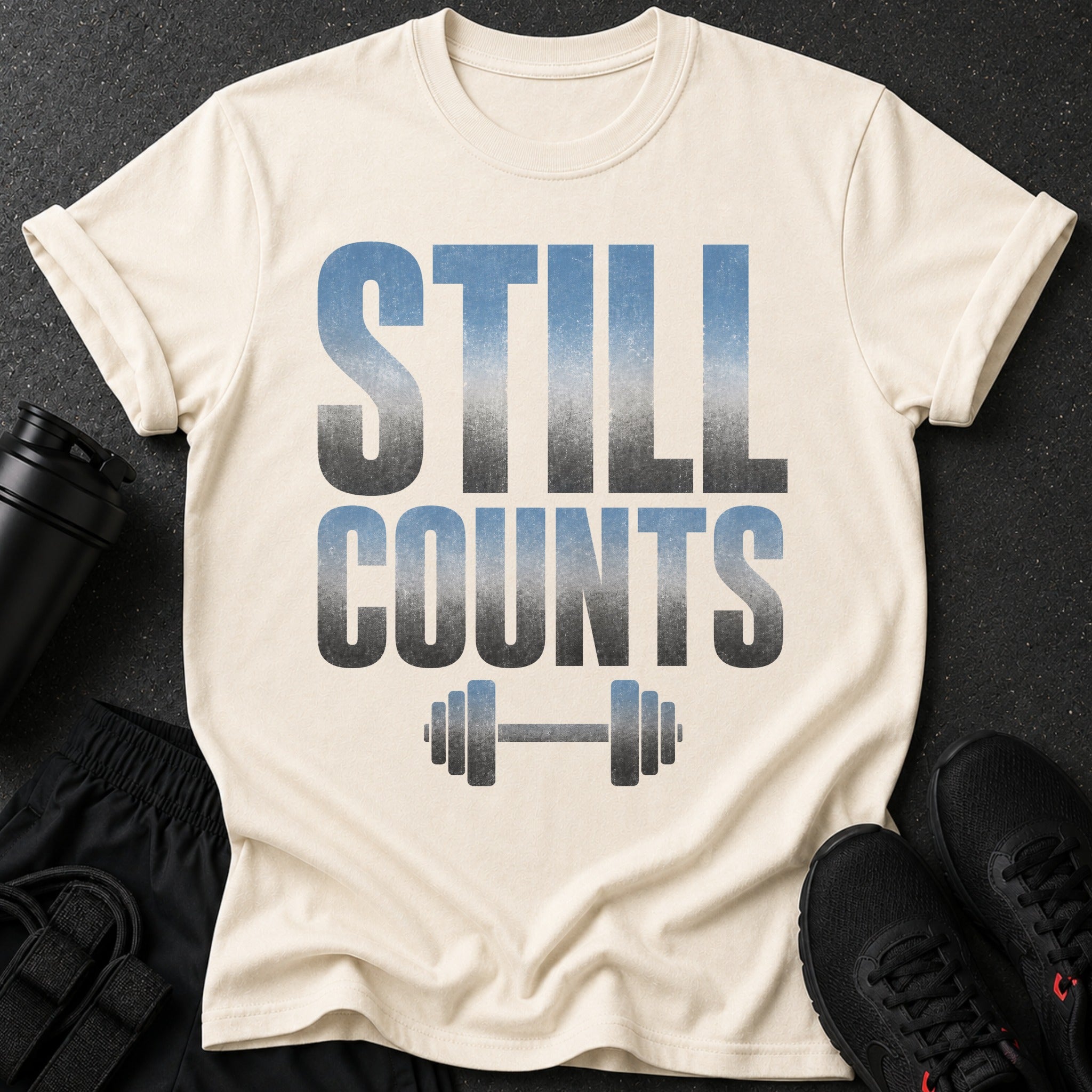 Cream t-shirt with "STILL COUNTS" text and dumbbell graphic.