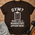Brown t-shirt with "GYM? MORE LIKE A MANDATORY APPOINTMENT" text and checklist graphic.