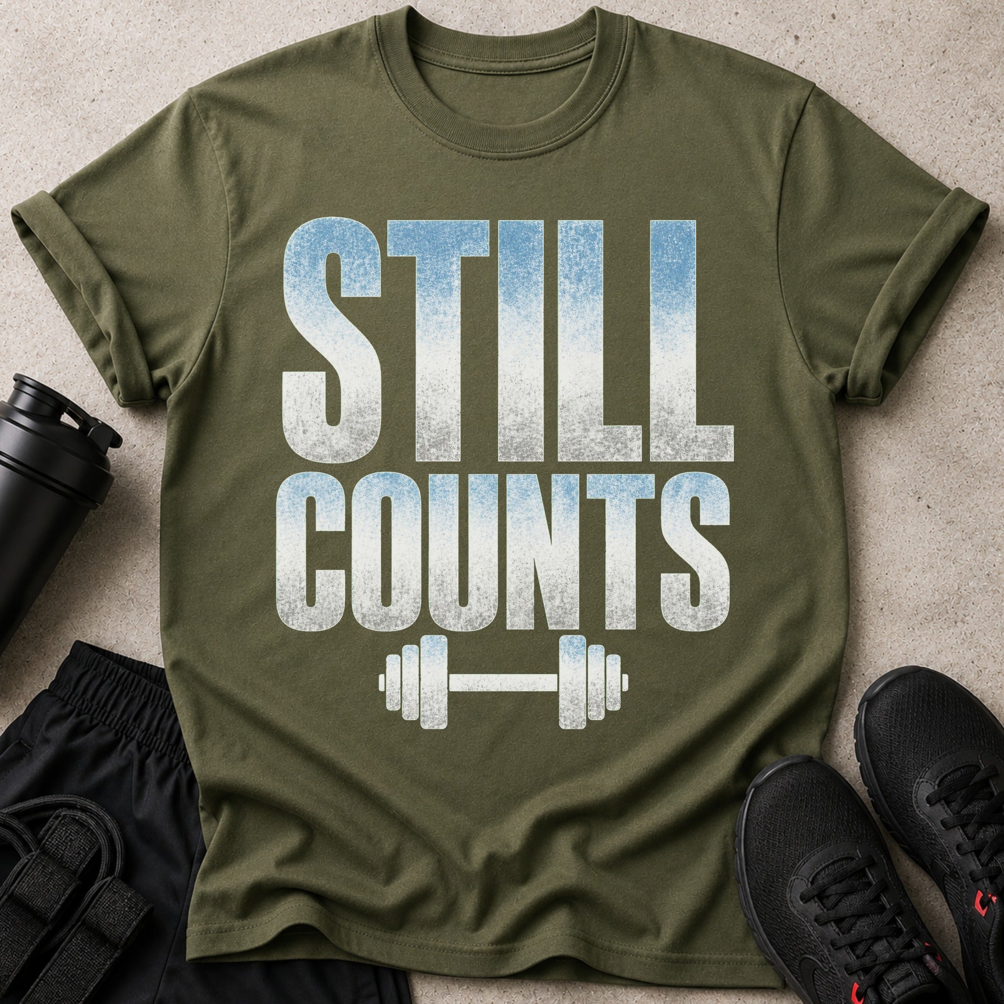 Olive green t-shirt with "STILL COUNTS" text and barbell graphic.