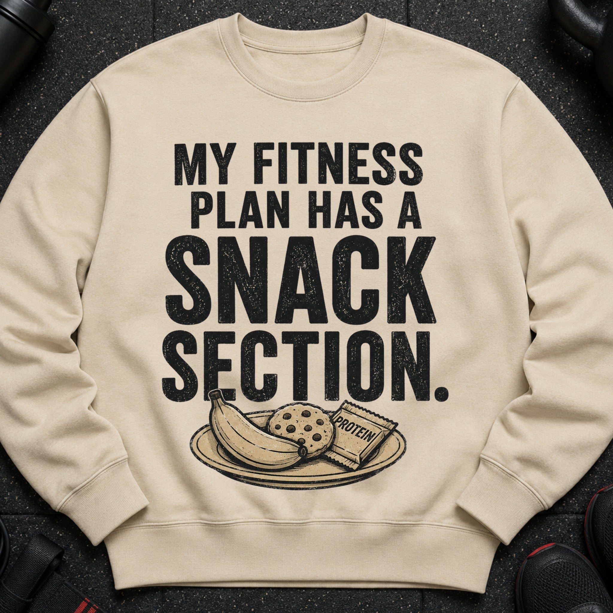 Light beige sweatshirt with "My Fitness Plan Has a Snack Section" text and snacks.