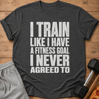 Dark grey t-shirt with white text: "I TRAIN LIKE I HAVE A FITNESS GOAL I NEVER AGREED TO".