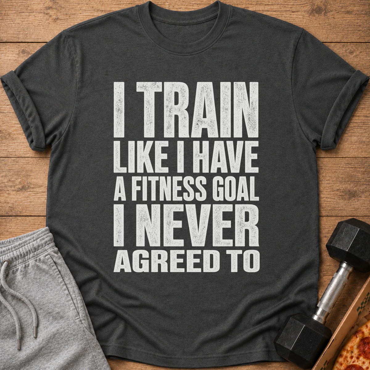 Dark grey t-shirt with white text: "I TRAIN LIKE I HAVE A FITNESS GOAL I NEVER AGREED TO".