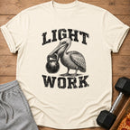 Cream t-shirt with a pelican holding a kettlebell, reading "LIGHT WORK".
