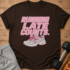 Brown t-shirt with pink text "RUNNING LATE COUNTS." and a pink bow on a sneaker.