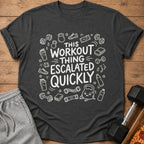 Dark grey t-shirt with white text "This workout thing escalated quickly" and gym graphics.