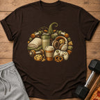 Brown t-shirt with graphic of gym items, coffee, and gaming controller.