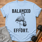 Light blue t-shirt with a flamingo wearing sunglasses holding a kettlebell and text "BALANCED EFFORT."
