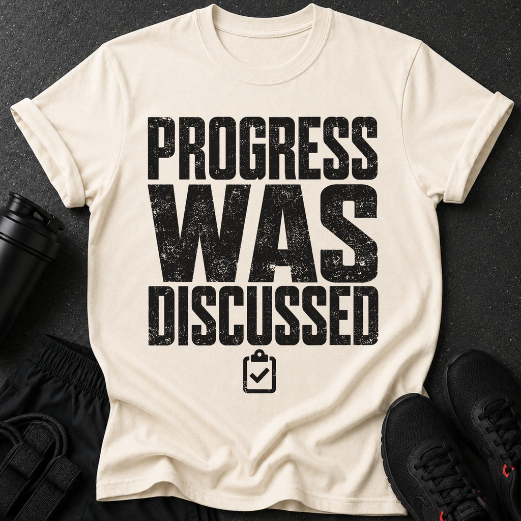 Cream t-shirt with black distressed text "PROGRESS WAS DISCUSSED" and a checklist icon.