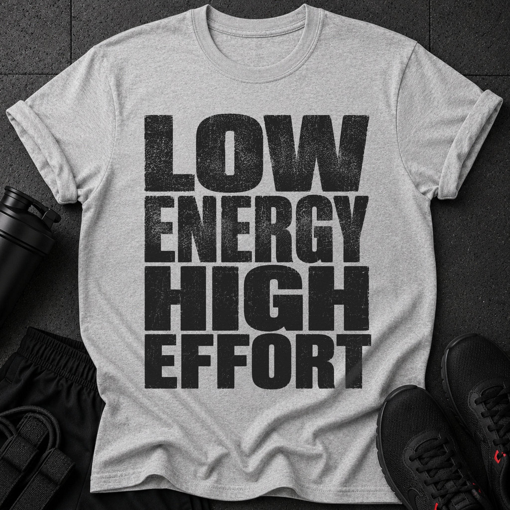 Gray t-shirt with "LOW ENERGY HIGH EFFORT" text, black athletic shorts, and shoes.