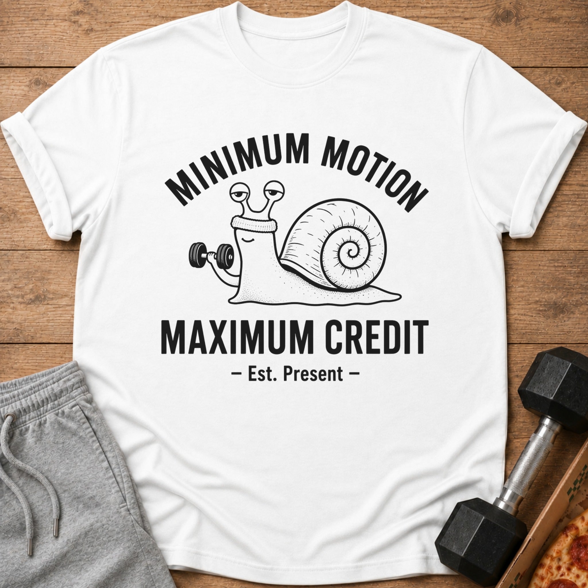 White t-shirt with a snail lifting a dumbbell and text "Minimum Motion Maximum Credit".
