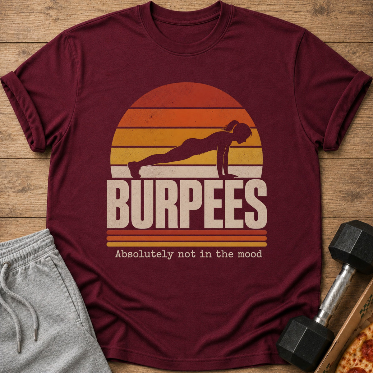 Maroon t-shirt with sunset graphic, silhouette of woman doing a burpee, and text "BURPEES Absolutely not in the mood".