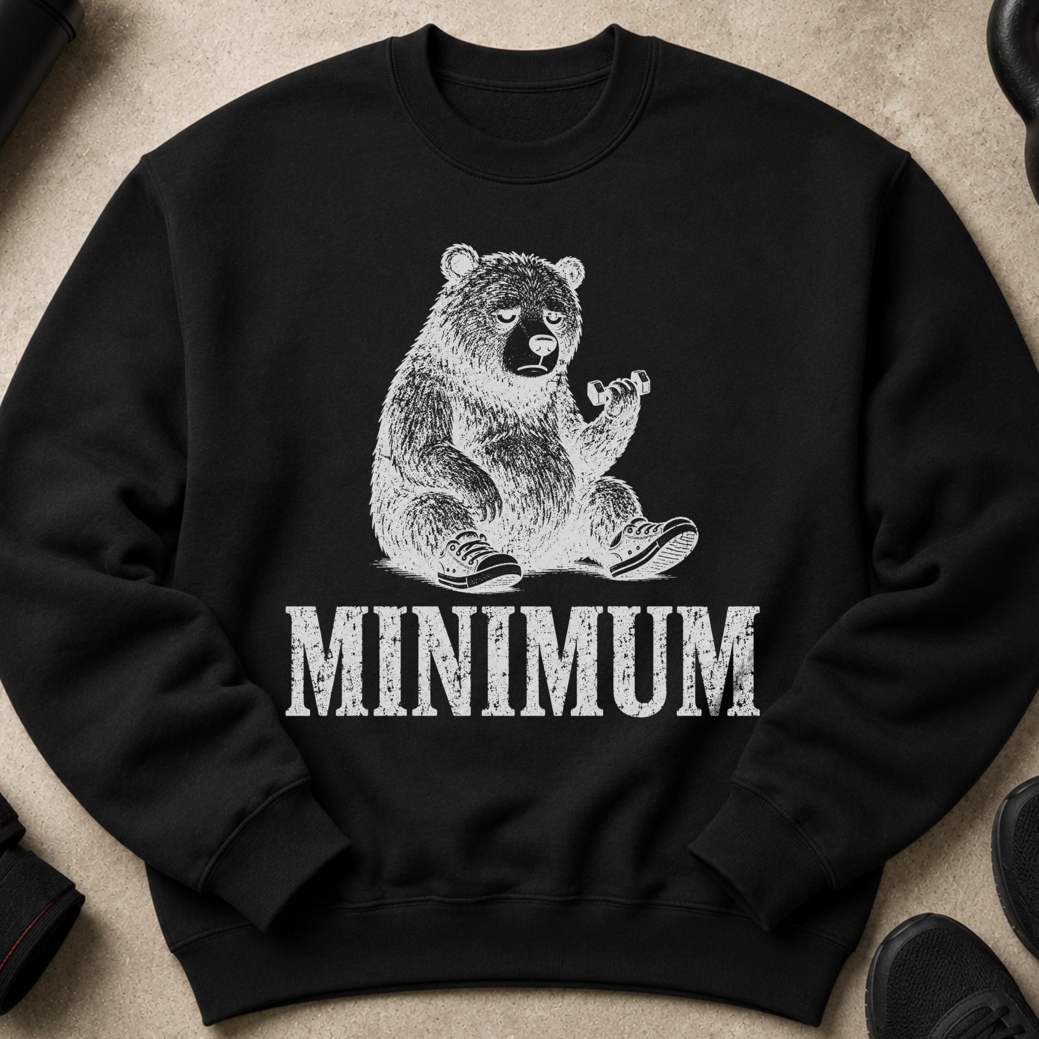 Black crewneck sweatshirt with a graphic of a tired bear lifting a dumbbell and the word "MINIMUM".