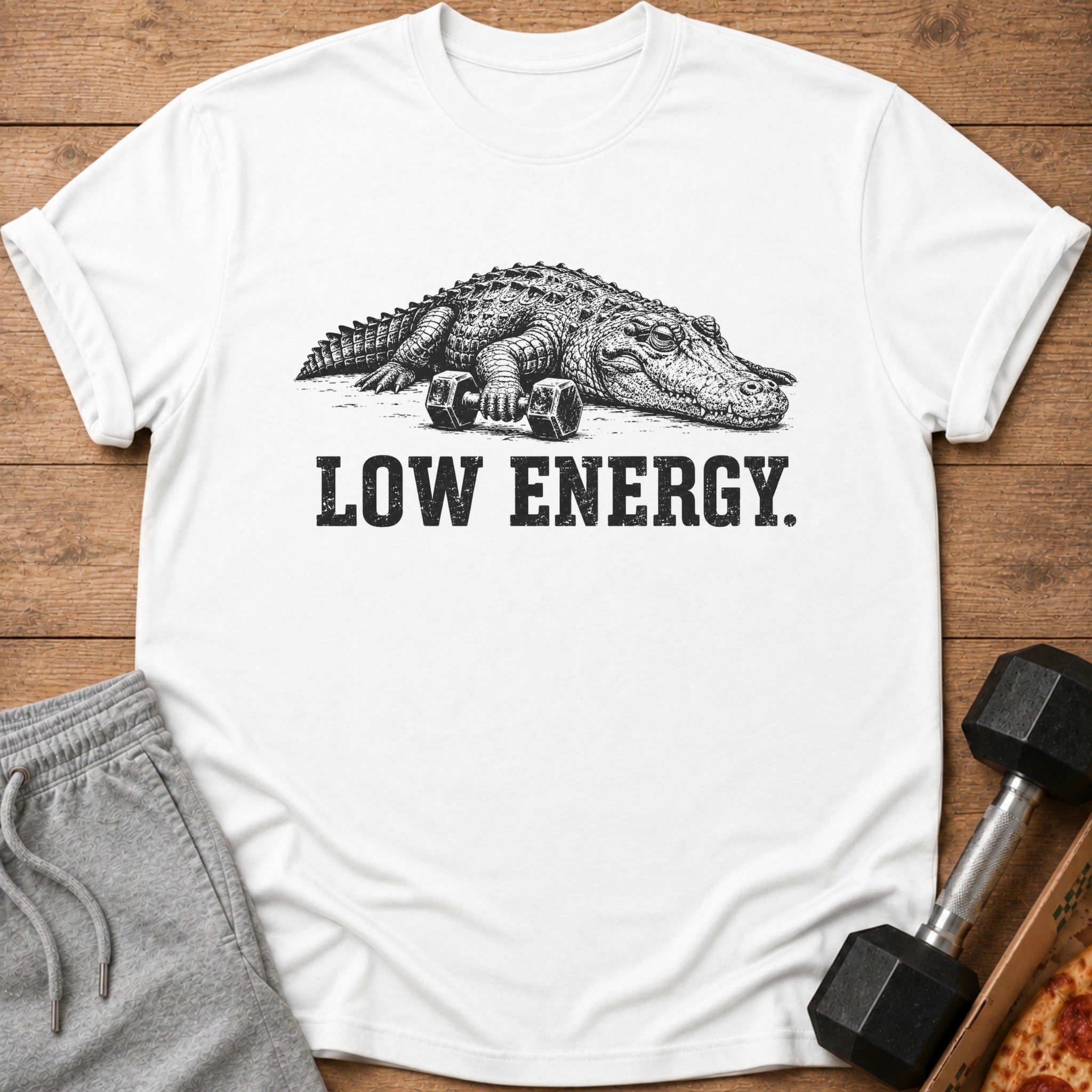 White t-shirt with a distressed graphic of an alligator resting on dumbbells and text "LOW ENERGY."