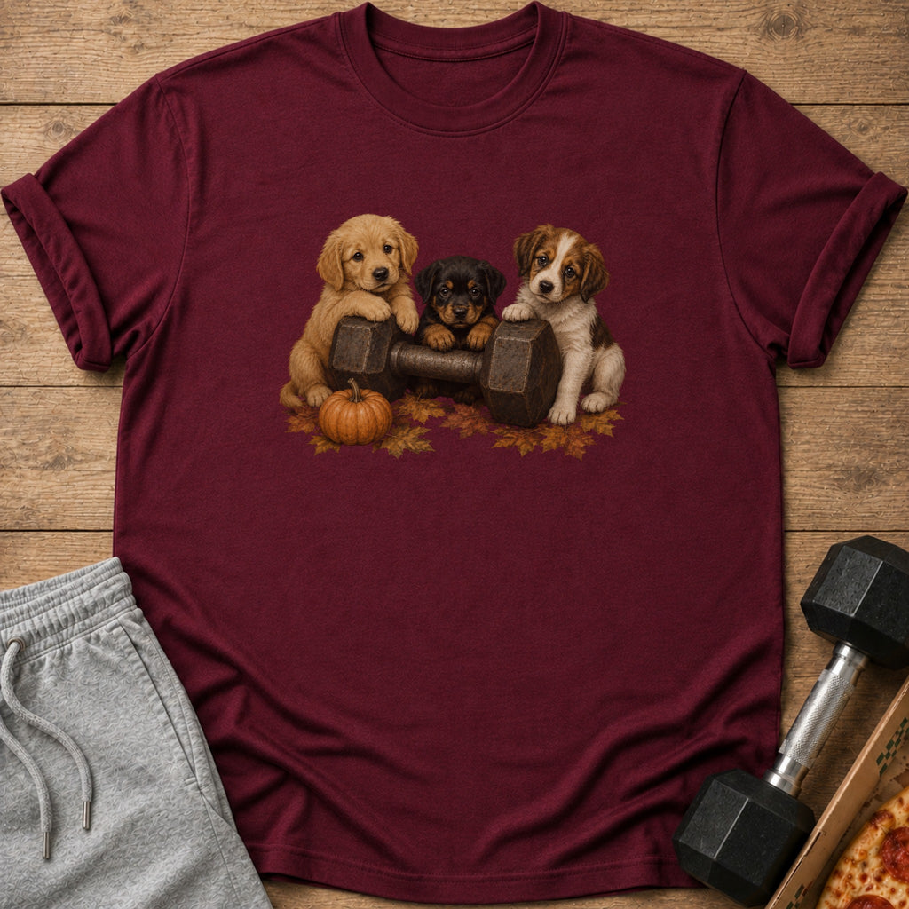 Three puppies sit behind a dumbbell with a pumpkin and fall leaves.