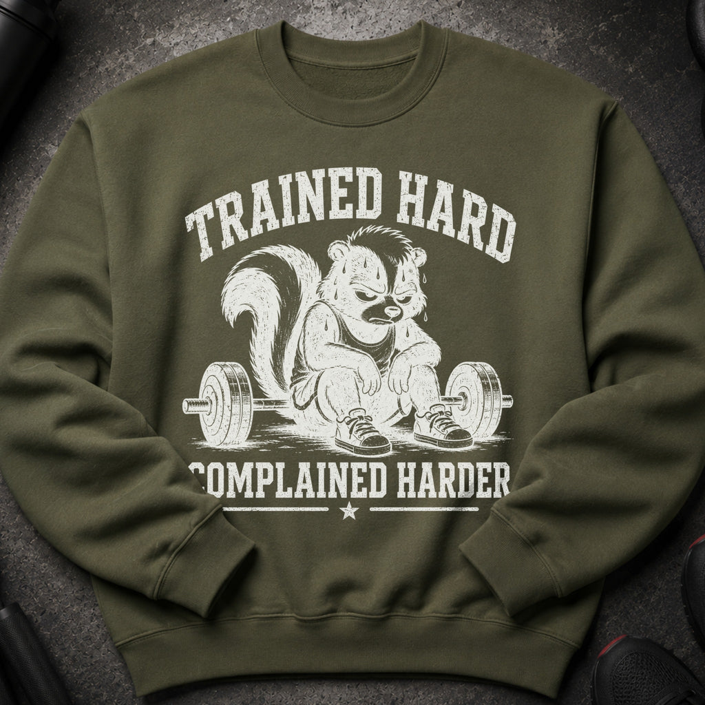 Olive green sweatshirt with distressed graphic of skunk sitting on barbell, text: "TRAINED HARD COMPLAINED HARDER".
