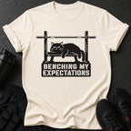 T-shirt with black cat on weight bench graphic and text "BENCHING MY EXPECTATIONS".