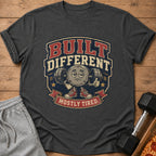 T-shirt with "BUILT DIFFERENT MOSTLY TIRED" text and a cartoon character lifting weights.
