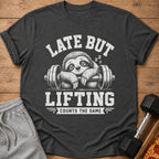 Dark gray t-shirt with a sleeping sloth on a barbell, reading "LATE BUT LIFTING COUNTS THE SAME".