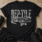 Black t-shirt with white "REP-TILE" text and an alligator holding a dumbbell.