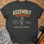 Dark gray t-shirt with "Assembly Required" and a tired boy between a gym bag and dumbbell.