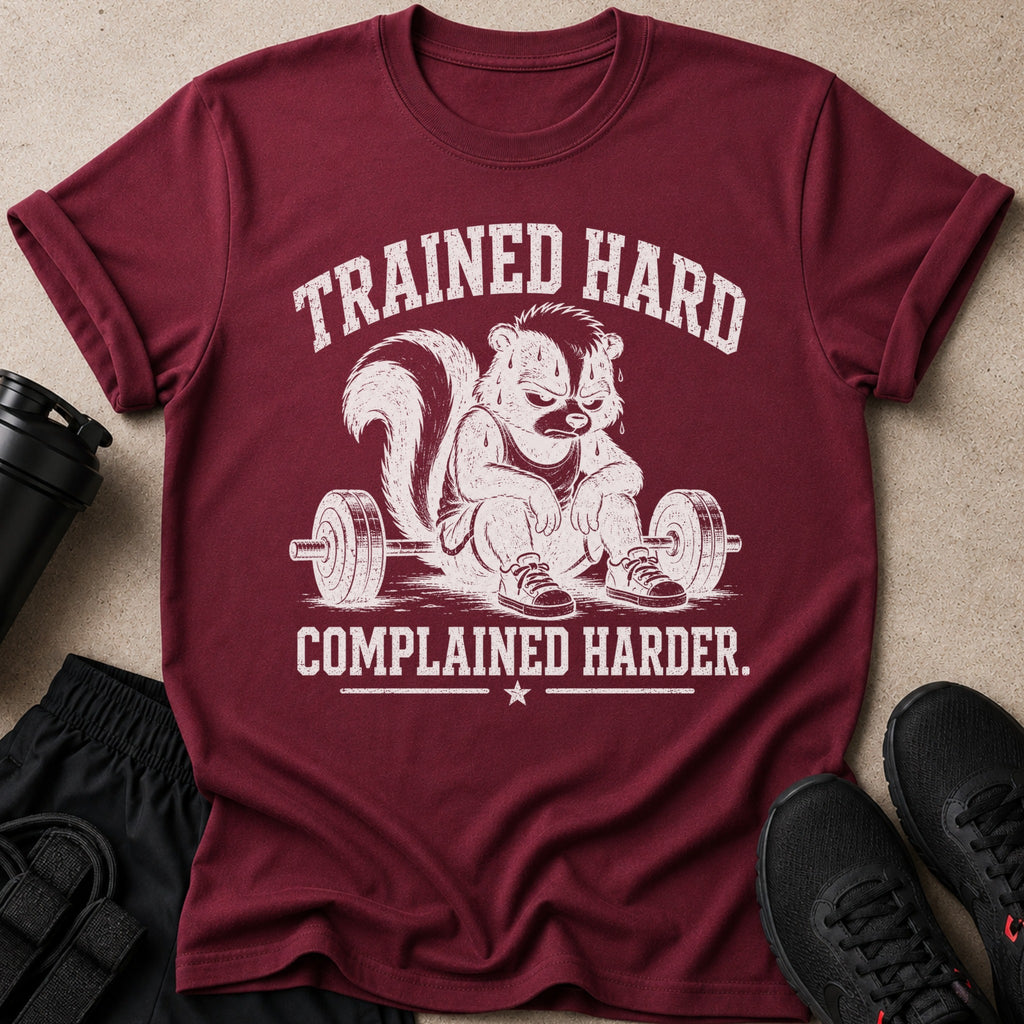 Maroon t-shirt with distressed graphic of a skunk lifting weights reading "TRAINED HARD. COMPLAINED HARDER."