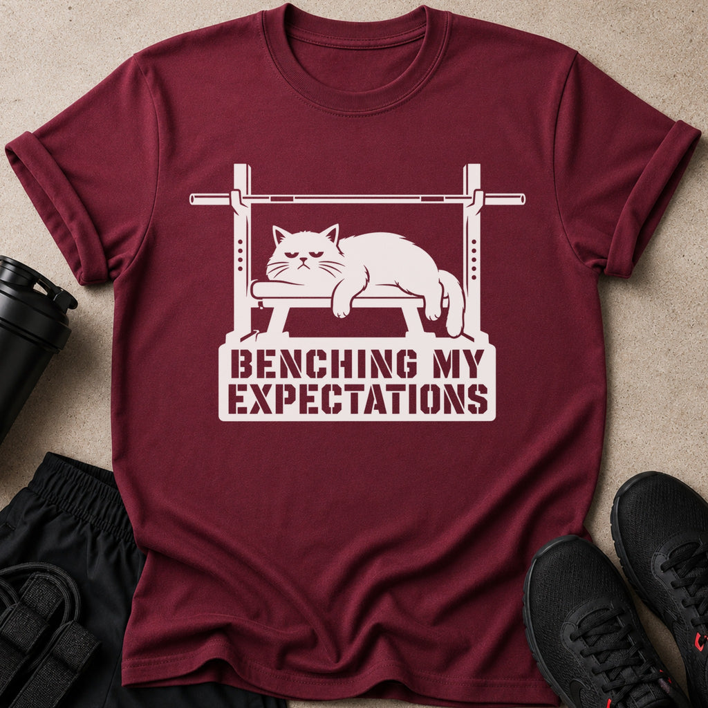 Maroon t-shirt with graphic of a cat on a barbell, reading "Benching My Expectations."