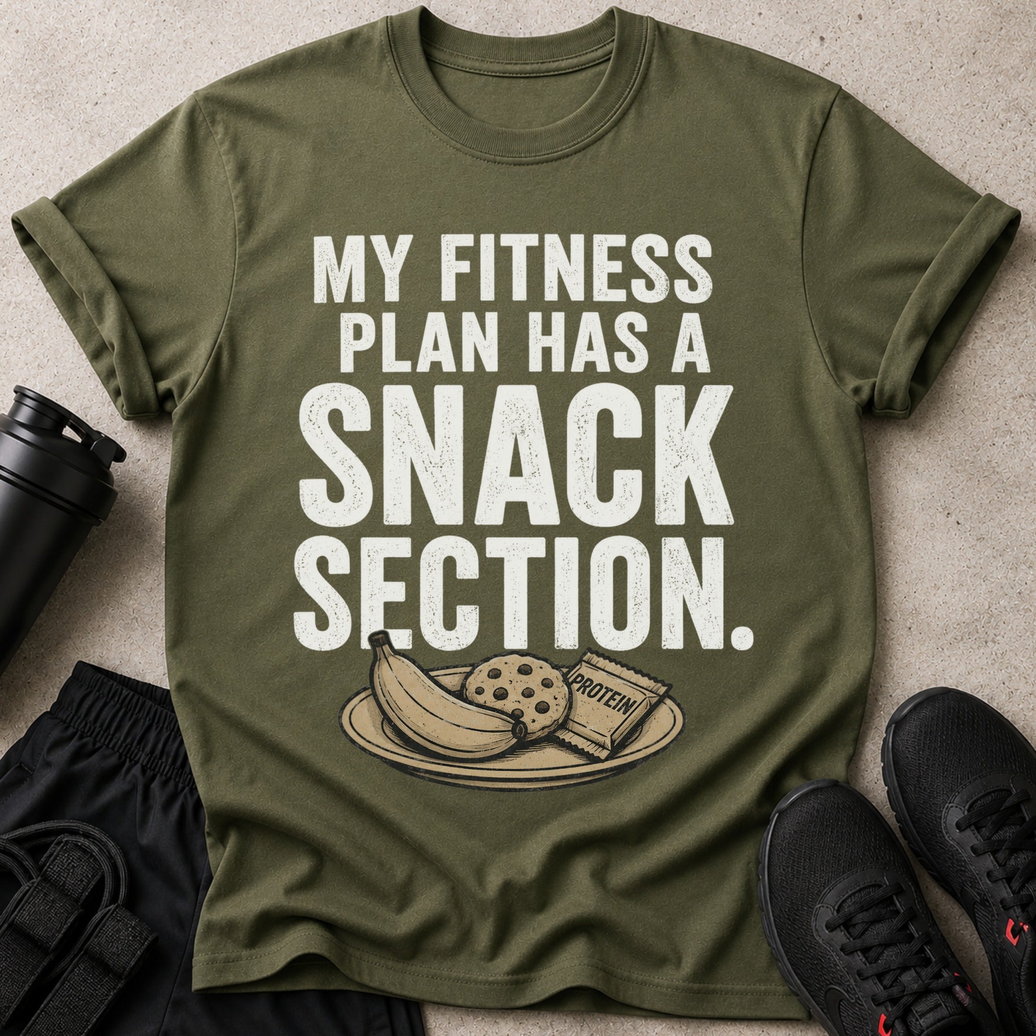 Olive green t-shirt with text "MY FITNESS PLAN HAS A SNACK SECTION" and graphics.