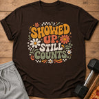 Brown t-shirt with "Showed Up Still Counts" text and retro floral graphics.